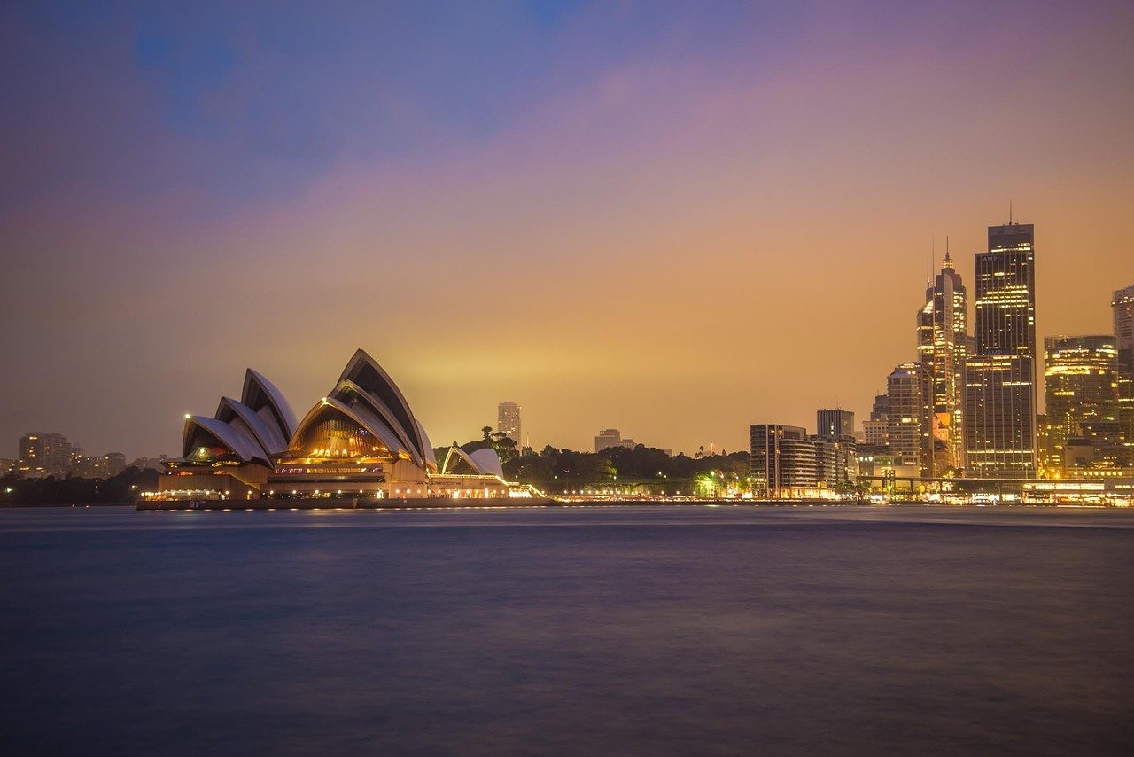 Sydney Opera House illuminated at night beside the harbour