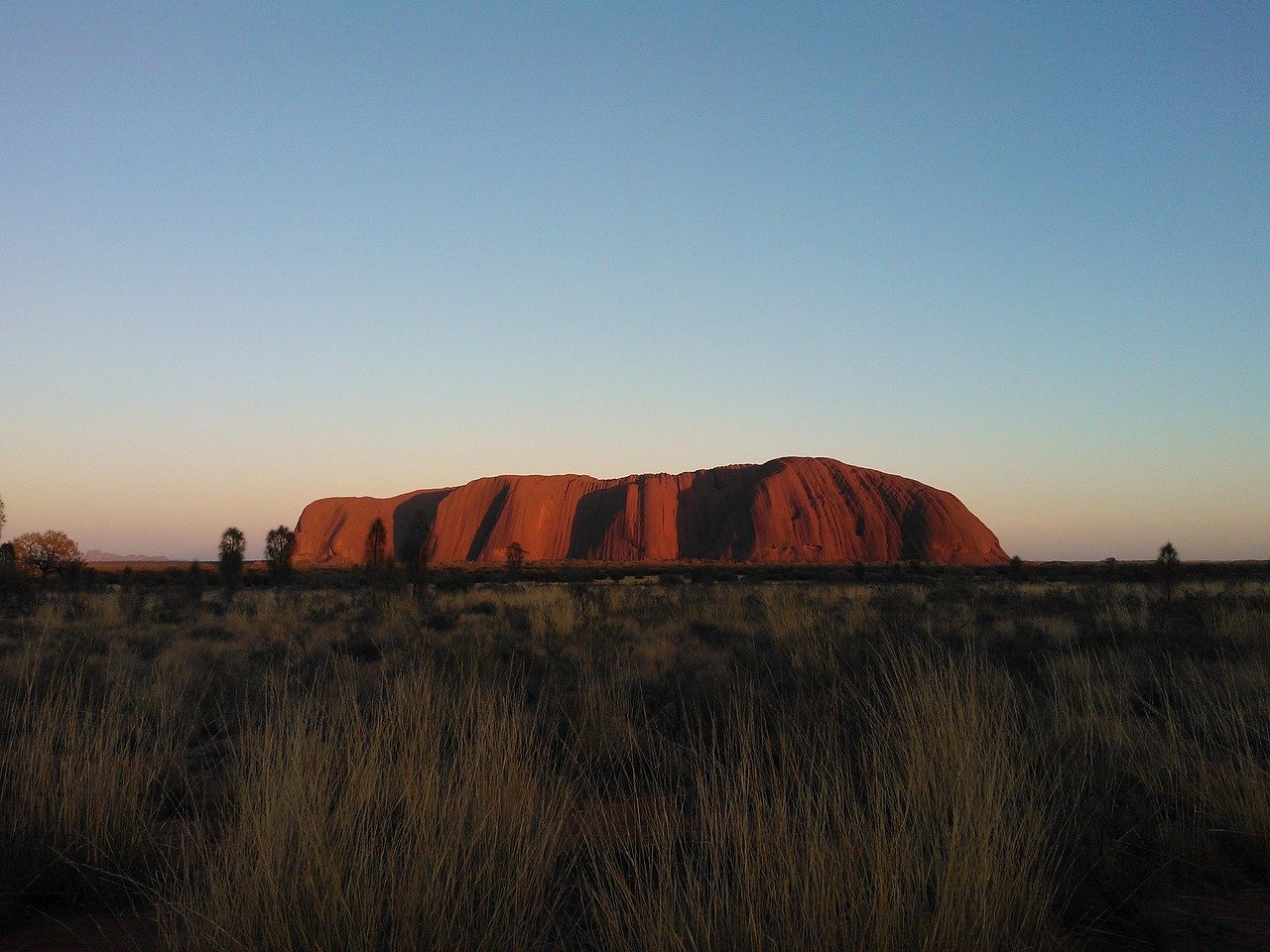 Uluru Ayers Rock at sunrise glowing orange in the Australian outback